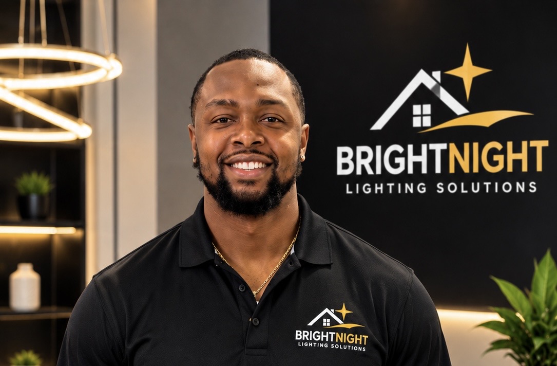 Julien Gums, owner of BrightNight Lighting Solutions, standing in front of the BrightNight logo